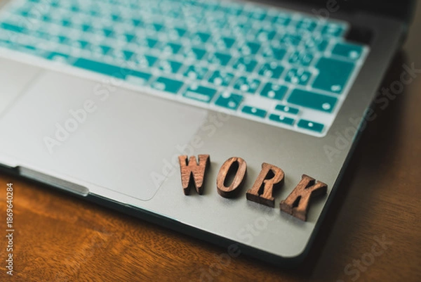 Obraz 木のデスクに置かれたノートパソコンとWORKの文字