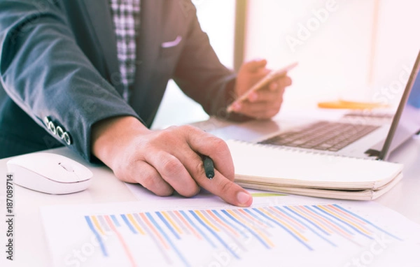 Fototapeta accounting,financial,close up of business man hand working on laptop computer with business graph information diagram on wooden desk as concept,vintage,selective focus