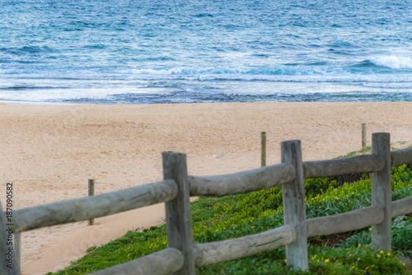 Obraz Scenic view of abandoned sandy beach and ocean waves, wooden fence in foreground. Empty Mona Vale beach, Sydney northern beaches, Australia.