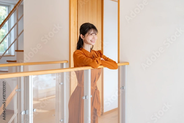 Obraz オレンジ色のワンピースを着た女性が、手すりに寄りかかりながら明るく微笑んでいるカット