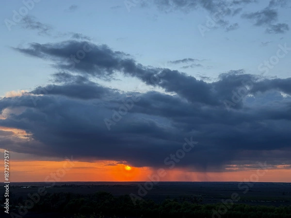 Obraz Sunset creating orange glow under rain clouds