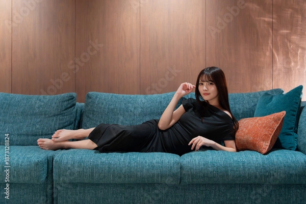 Obraz ソファに横たわる黒いドレスを着た笑顔の日本人女性モデル