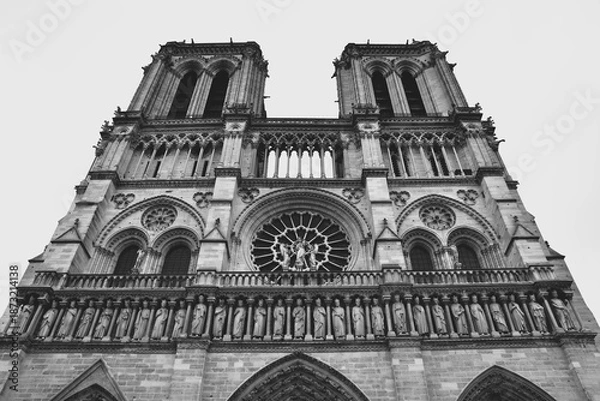 Obraz フランスのパリにある世界遺産ノートルダム大聖堂の正面ファサードを捉えたモノクロ写真 歴史的なゴシック建築の精密な彫刻や薔薇窓が際立つ白黒のアート 荘厳で神聖な雰囲気を表現したカトリック教会の風景素材