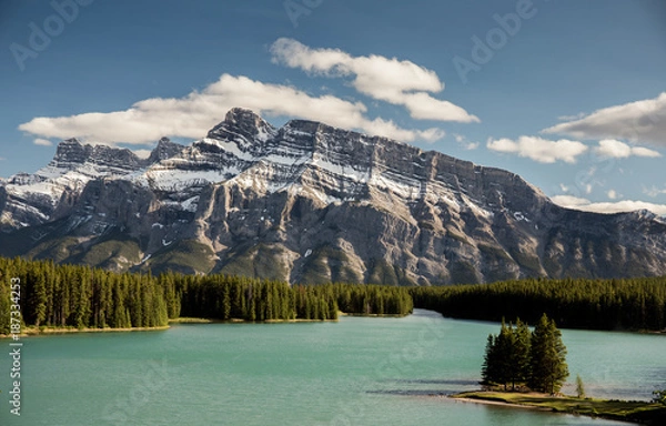 Obraz Two Jack Lake with Mount Rundle. A sunny day with a few clouds over the mountain. The lake is a turquoise color and trees are a rich green. There is snow on mount Rundle.
