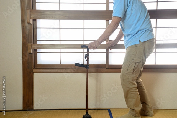 Obraz 杖を使用して室内でリハビリをしている老人