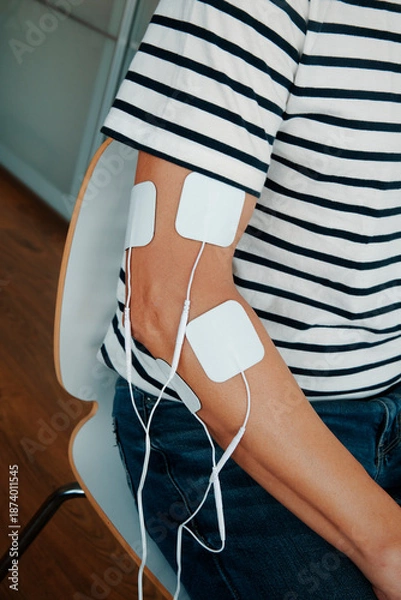 Obraz a man using a muscle stimulation device on his arm