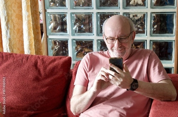 Obraz Elderly man relaxing at home using smartphone