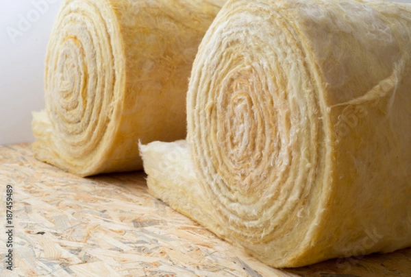 Fototapeta roll of mineral wool lying on the wooden floor