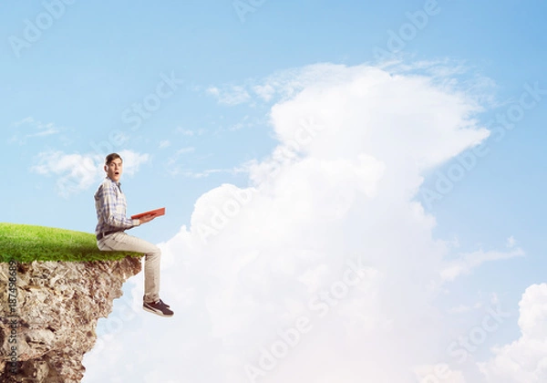 Fototapeta Student guy with book in hands preparing for exam