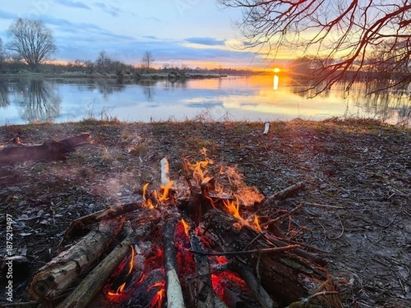 Obraz Sunset on the river with a fire, early spring.