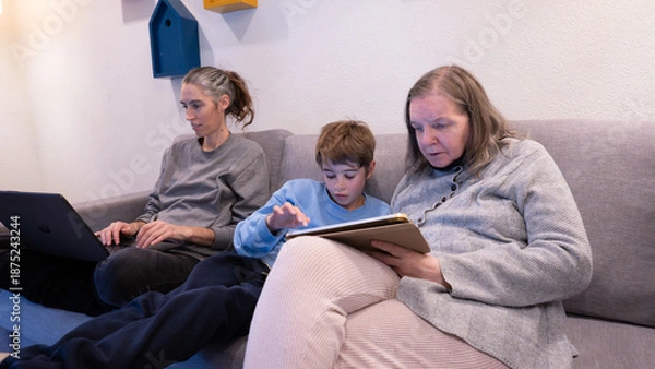 Obraz Multi-generational family members using digital devices on sofa