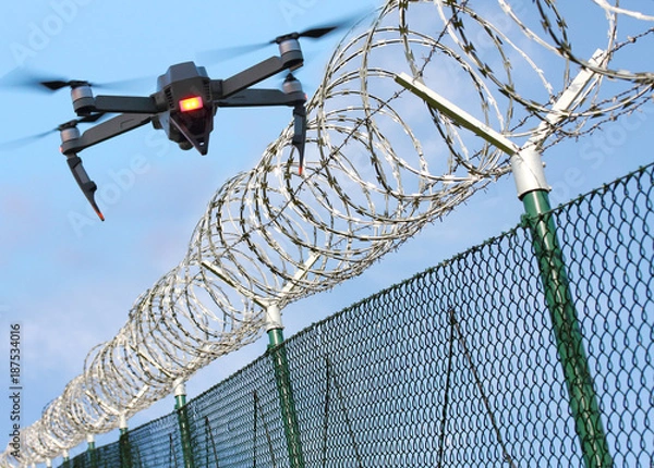 Fototapeta Drone monitorujący ogrodzenie z drutu kolczastego na granicy stanu lub w strefie zastrzeżonej. Nowoczesna technologia dla bezpieczeństwa.