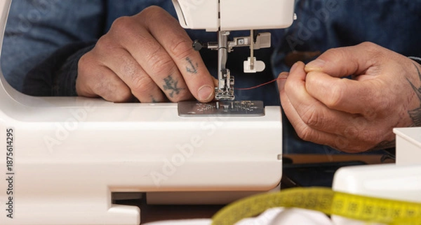 Obraz Craftsperson hands threading sewing machine needle with red thread