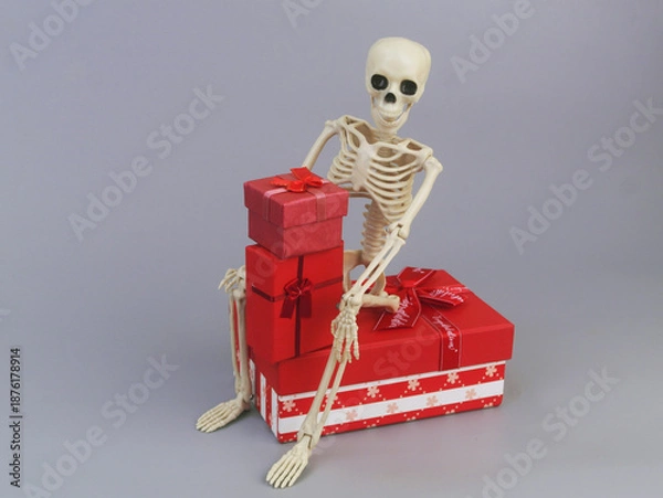 Obraz Human skeleton with red gift boxes on grey background.	