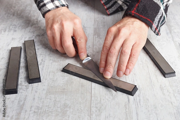 Obraz Sharpening small kitchen knife on white table.