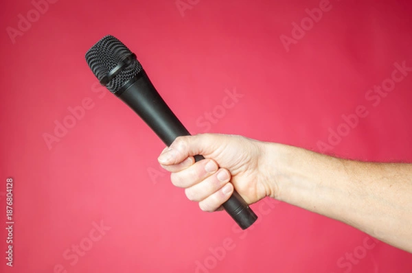 Obraz Wireless microphone in hand on a red background