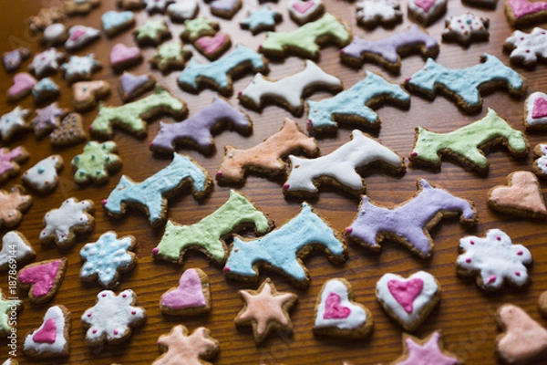 Fototapeta Имбирное печенье в разноцветной сахарной глазури в форме собак, сердец, цветов и звезд на деревянном столе