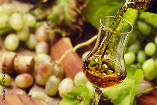 Obraz Golden Grappa wlewa się w szklankę, rustykalne martwą ilość, selektywne skupienie