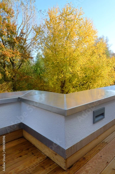 Fototapeta View from the terraces at the autumn landscape of the forest. The terrace wall is bent incorrectly. The forest in the background is in autumn colors. The wild and urban environment is visible. 