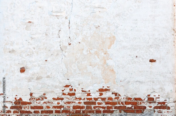 Fototapeta Texture of old brick wall with peeling plaster. Beautiful background of old brickwork of the historic building.
