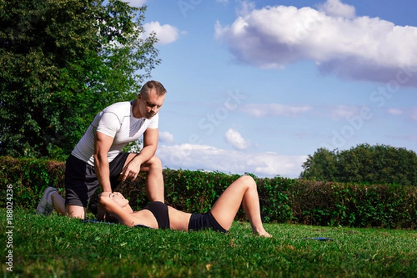 Obraz The coach looks like the girl does exercise on the abdominal muscles.