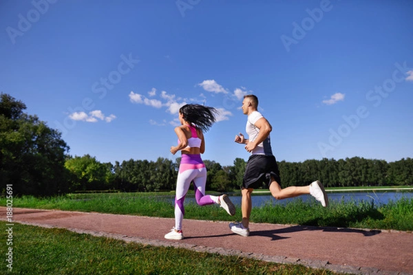 Obraz Man and woman doing Jogging in the Park near the water.