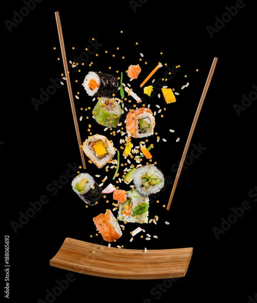 Fototapeta Pływające kawałki sushi z drewnianymi pałeczkami i talerz, na białym tle na czarnym tle.