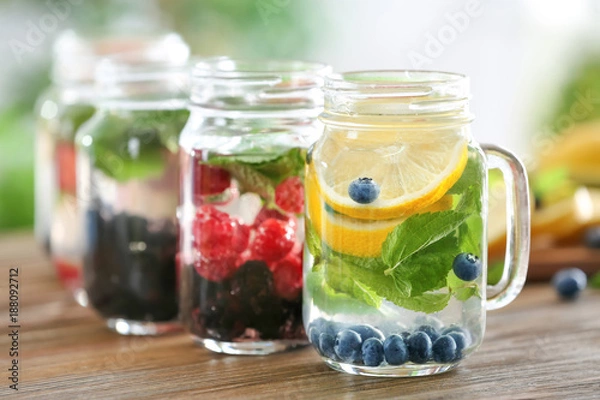 Fototapeta Mason jars of infused water with fruits and berries on wooden table