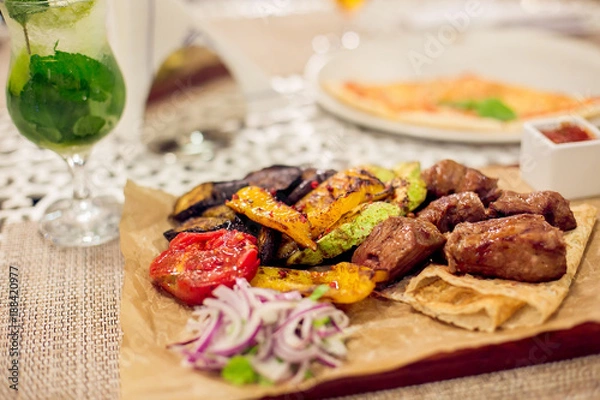 Fototapeta Meat and a variety of grilled vegetables on a wooden board