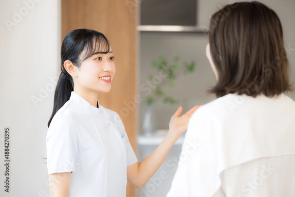 Obraz 看護師などの医療従事者が患者に向けて丁寧に説明し案内するクリニックの受付などのシーン　こちらです 患者の顔無し