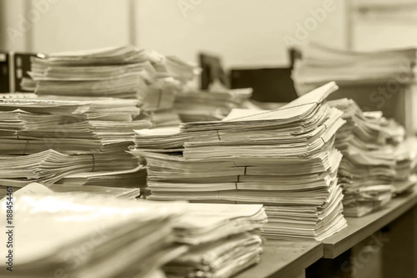 Fototapeta bundles bales of paper documents. stacks packs pile on the desk in the office in black and white. mountain of waste paper