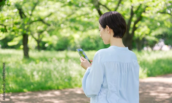 Obraz 屋外でスマートフォンを使う40代女性　後ろ姿