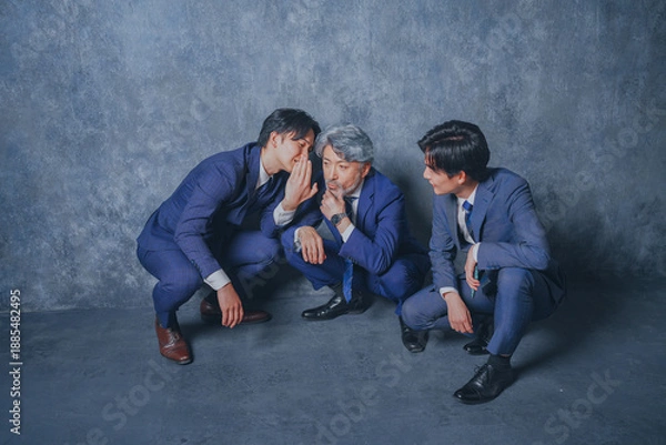 Fototapeta 座り込んで噂話をするスーツ姿のビジネスマン3人