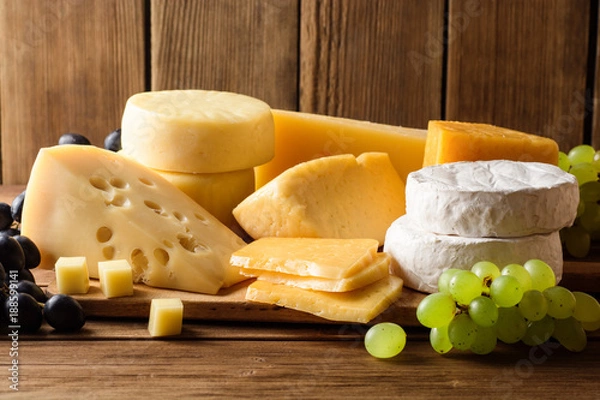 Fototapeta Various types of cheese on dark rustic wooden background.