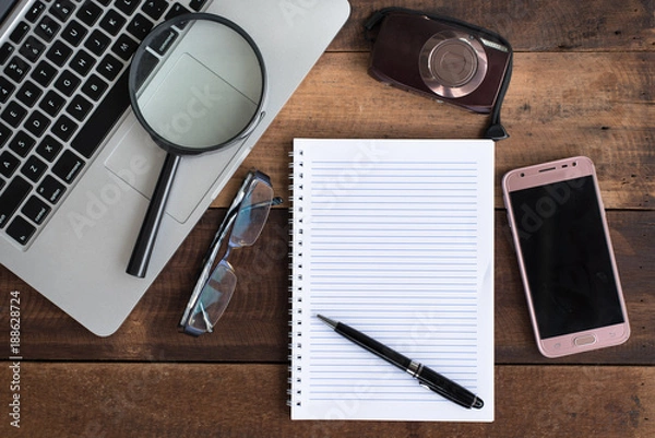 Fototapeta Laptop, Notebook, smartphone, spectacle, camera and magnifying glass on wooden table. online job, journalist and business concept