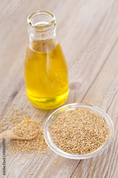 Fototapeta Bottle of flax seed oil ans seeds on wooden table.
