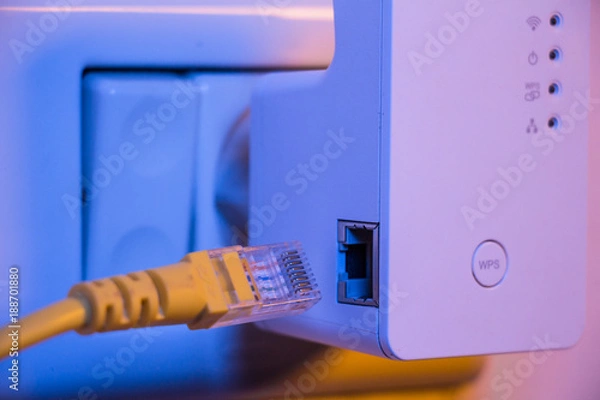 Obraz Insert ethernet cable into WiFi extender device which is in electrical socket on the wall