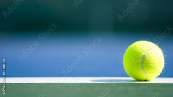 Fototapeta one new tennis ball on white line in blue and green hard court with light from right, shadow and copy space on left