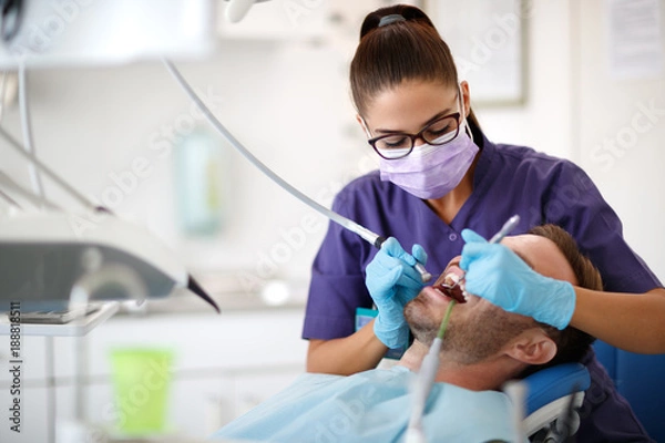 Fototapeta Młoda kobieta dentysta wiercenia zęba do pacjenta