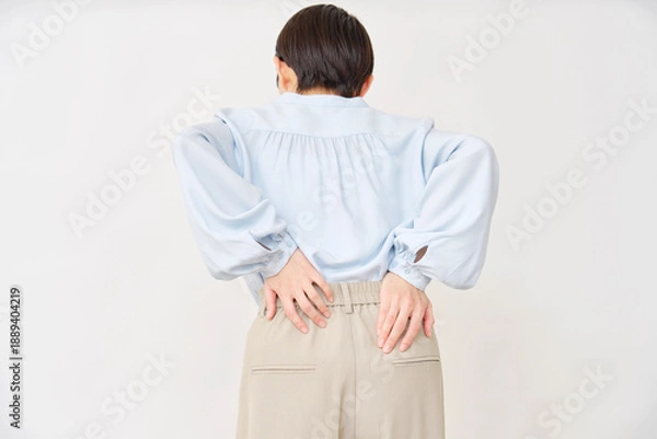 Obraz 40代の女性　腰痛　白背景　後ろ姿