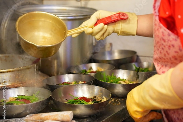 Fototapeta 전통시장 맛집 주방에서 커다란 양은 국자로 진하게 우려낸 육수를 칼국수 그릇에 담아내는 정겨운 모습