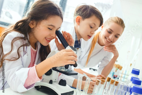 Fototapeta Little kids with teacher in school laboratory looking in microscope