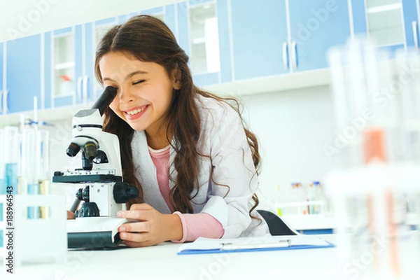Fototapeta Little child with learning class in school laboratory using microscope