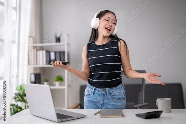 Obraz Young woman enjoying music while working remotely