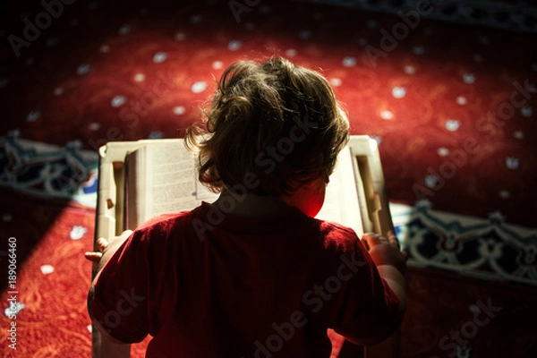 Obraz Young boy reading a book (Quran) 