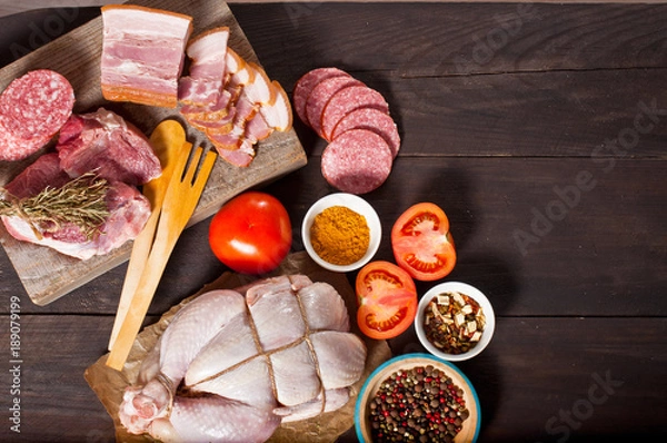 Obraz Chicken carcass, meat and delicacies on a wooden table. Dark background, top view.