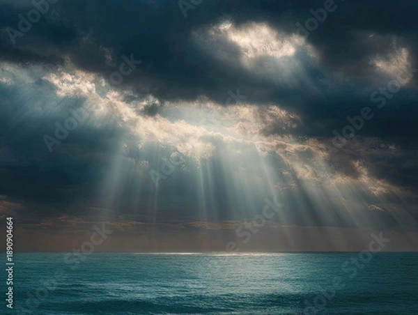 Obraz Dramatic light beams pierce dark clouds over a calm, rippling ocean