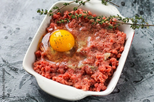 Obraz Raw ground beef with chicken egg and spices with thyme
