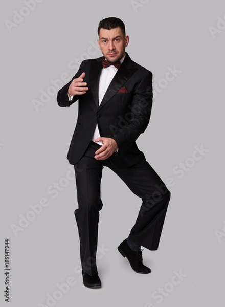 Fototapeta Full length portrait of a handsome guy in tuxedo