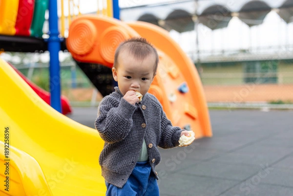 Obraz Toddler enjoying bread while playing at playground
